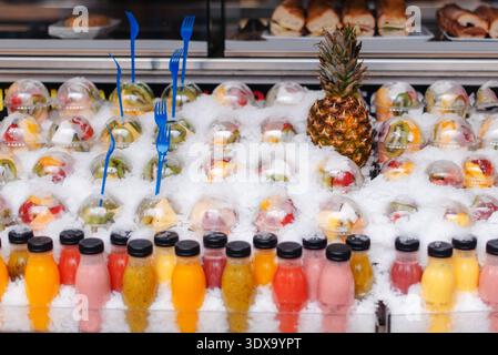 Le tazze di frutta e i succhi di frutta sono esposti sul ghiaccio in una bancarella del mercato di Barcellona Foto Stock