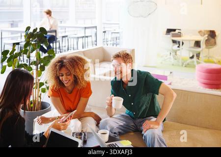 Vista dall'alto dell'imprenditore maschile felice seduto con colleghi sul divano nella hall dell'ufficio Foto Stock