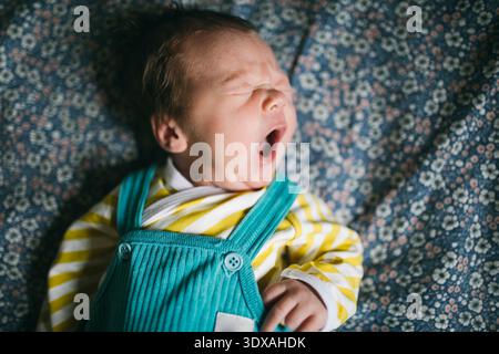 Direttamente sopra l'immagine di un simpatico bambino che sbadiglia mentre si sdraia sul letto Foto Stock