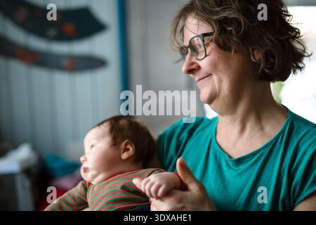 Donna anziana sorridente che tiene per mano il nipote a casa Foto Stock