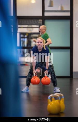 Donna matura che si allena con il kettlebell in palestra Foto Stock
