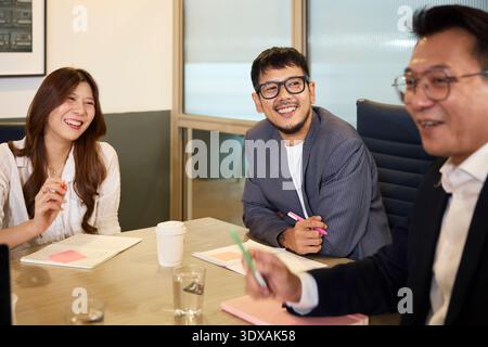 Colleghi di sesso maschile e femminile sorridenti seduti con il manager nella sala riunioni Foto Stock