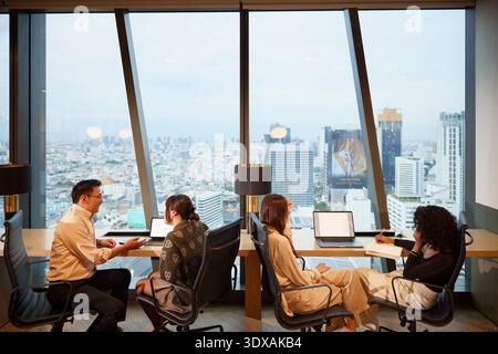 Gruppo di imprenditori uomini e donne seduti su sedie mentre lavorano in ufficio Foto Stock