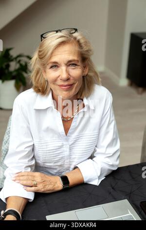 Ritratto di una donna anziana sorridente seduta alla scrivania di casa Foto Stock