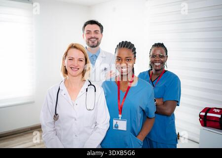 Team medico diversificato in piedi insieme sorridendo in ospedale Foto Stock