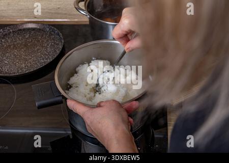 Versare l'aceto di riso in una pentola di riso, aggiungere zucchero, ingredienti per il sushi, riso cinese bianco in una pentola, preparare il sushi a casa, una ricetta fatta in casa Foto Stock