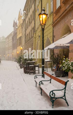 La neve copre una strada tranquilla di Praga durante la sera d'inverno, con la luce che splende da un lampione Foto Stock