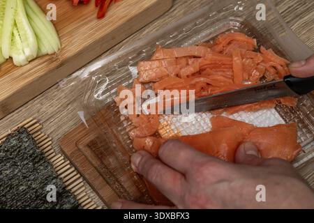 Salmone tagliato a fette ​​smoked su una tavola di legno, preparando il tradizionale sushi giapponese, cibo salutare, cibo cinese a casa Foto Stock