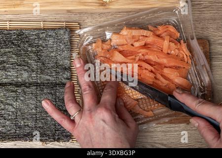 Salmone tagliato a fette ​​smoked su una tavola di legno, preparando il tradizionale sushi giapponese, cibo salutare, cibo cinese a casa Foto Stock