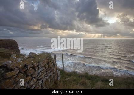 Nuvole di tempesta e raggi del sole sulle onde dell'Atlantico viste dalle scogliere calcaree sulla Glamorgan Heritage Coast, Galles, Regno Unito. Foto Stock