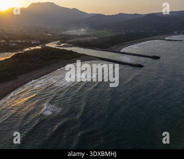 Vista aerea della luce dorata del sole che baciano le acque scure mentre incontrano la riva vicino alle montagne, Keelung, Keelung City, Taiwan. Foto Stock