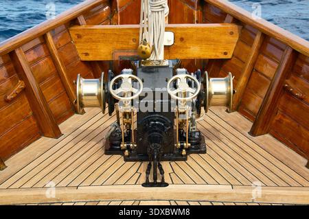 Barca d'epoca in legno con verricello a salpancora di ancora sulla terrazza in teak a mare Foto Stock