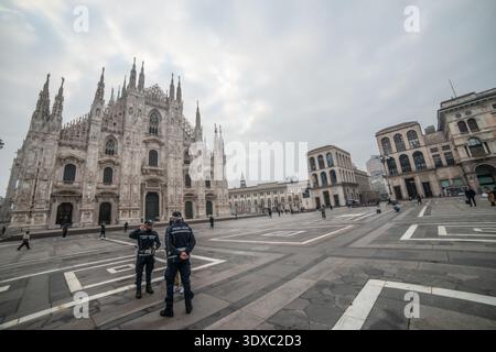 Milano Italia 27 febbraio 2026: Due poliziotti locali osservano la piazza di fronte al Duomo di Milano mentre un ciclista attraversa lo spazio urbano su una cl Foto Stock