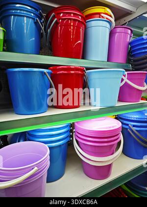 Ripiano rifornito con più secchi in vari colori organizzati sugli scaffali, che mostrano le loro vivaci tonalità. Foto Stock