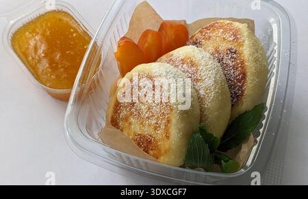 Un delizioso cestino per la colazione con soffici pancakeswith peach jam Syrniki Foto Stock