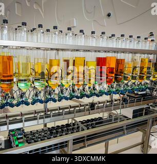 Produzione di profumi. Profumi diversi in bottiglia. Linea di produzione robotizzata di profumi con erogazione automatica di fragranze Foto Stock