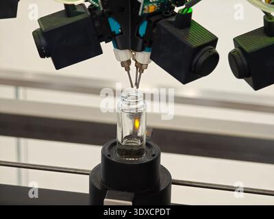 Produzione di profumi. Profumi diversi in bottiglia. Linea di produzione robotizzata di profumi con erogazione automatica di fragranze Foto Stock