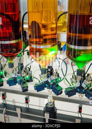 Produzione di profumi. Profumi diversi in bottiglia. Linea di produzione robotizzata di profumi con erogazione automatica di fragranze Foto Stock