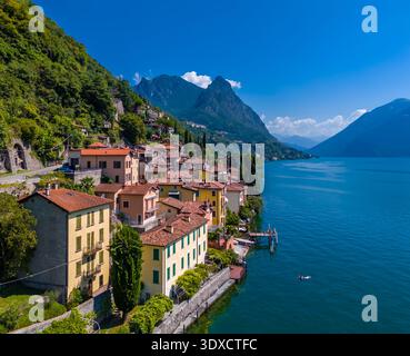 Lago di Lugano, Italia. Vista sul lago, sulle montagne e sul paesino panoramico. Una piccola città italiana sul lago sul confine della Svizzera. Vista aerea con drone Foto Stock