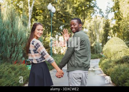 La coppia ama passeggiare in un parco tenendosi per mano e sorridendo davanti alla telecamera Foto Stock