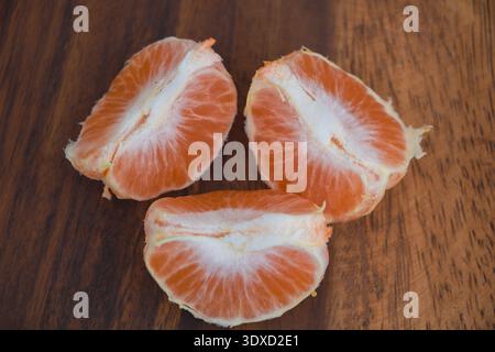 Segmenti di mandarino fresco su una superficie in legno - primo piano di agrumi succosi Foto Stock