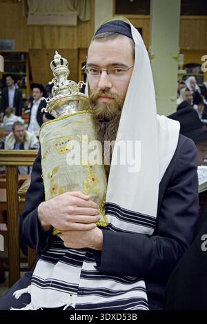 Adoratore che tiene la Torah personale del Rebbe Lubavitcher durante le funzioni mattutine di Pesach. Alla sinagoga principale di Chabad a Brooklyn nel 2013. Foto Stock