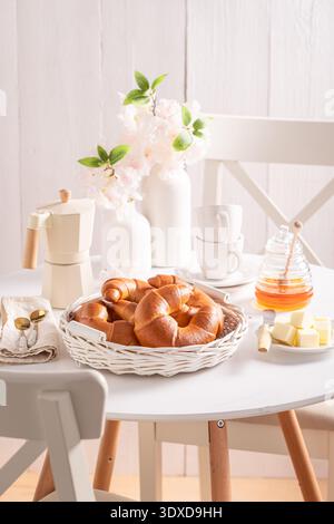 Croissant caldi e dorati serviti con caffè. Colazione con caffè, miele e burro. Foto Stock