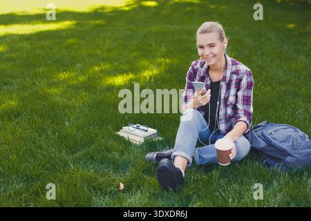 Incontra gli amici e bevi un caffè mentre sei seduto su Grass in un parco nel pomeriggio Foto Stock