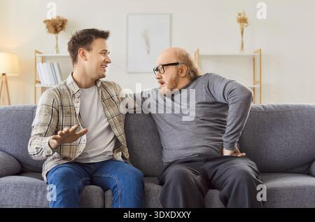 Allegro figlio e padre anziano che conversano a casa Foto Stock
