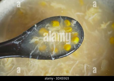 La zuppa con mais è servita in un mestolo nero Foto Stock