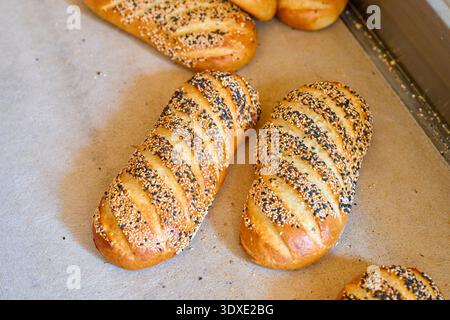 I pani bianchi a bacchetta appena sfornati si raffreddano presso la fabbrica del pane prima del confezionamento per la distribuzione ai mercati locali Foto Stock