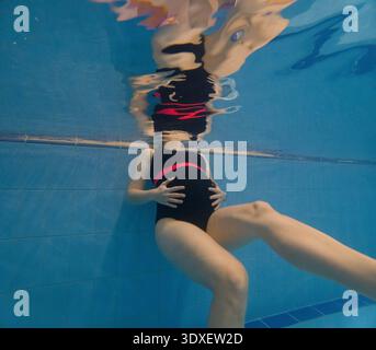 Donna incinta che galleggia sott'acqua in piscina Foto Stock