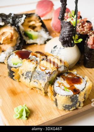 Varietà di sushi, evidenziando in primo piano diversi panini fritti in pastella di tempura serviti su una tavola di legno, Maiorca, Isole Baleari, Spagna Foto Stock