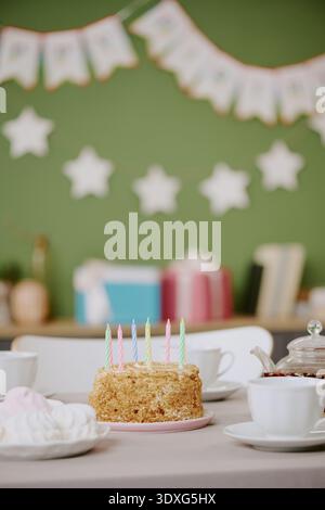 Torta di compleanno verticale con candele accese sul tavolo durante le festività Foto Stock