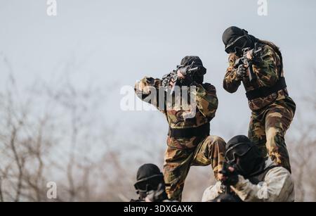 Squadra di paintball con marcatori mimetici durante una partita all'aperto Foto Stock