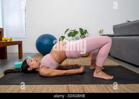Donna incinta che esegue l'esercizio di bridge su Mat Foto Stock