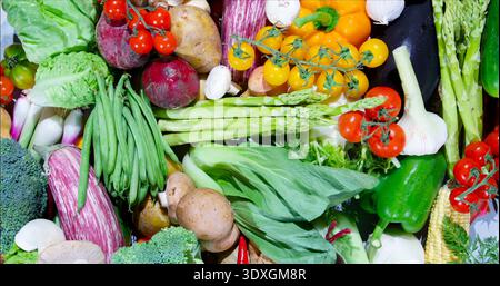 Verdure fresche disposte insieme su un tavolo in piena luce, catturando colori e forme diversi dei prodotti Foto Stock