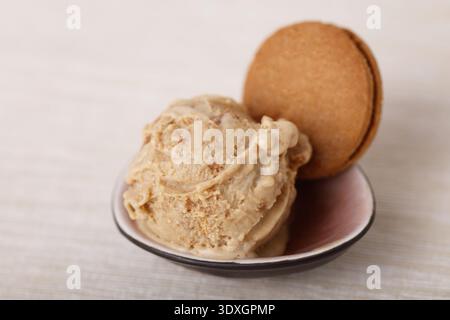 Una paletta di gelato cremoso al caramello condita con un biscotto al caramello, servito in una piccola ciotola Foto Stock