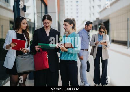 Colleghi di lavoro che discutono di documenti all'aperto durante una riunione urbana informale e una discussione di lavoro di squadra Foto Stock