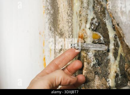 Ingegnere che ispeziona la riparazione epossidica di crepe in calcestruzzo. Primo piano della mano con l'imballatore per iniezione o l'ago di arresto dell'acqua con polimerizzazione epossidica. Fondazione o par Foto Stock
