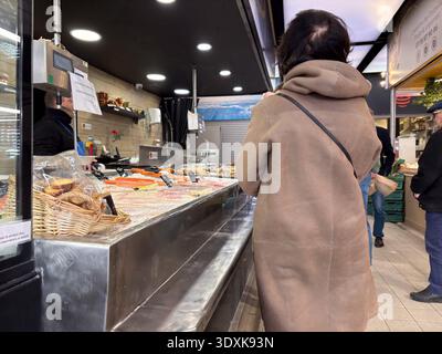 Donna che guarda la mostra di pesce fresco in una bancarella di pesce all'interno del mercato Les Halles Castellane a Montpellier, Francia. Mercato al coperto per lo shopping. Foto Stock