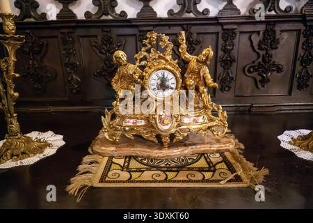 Grenada, Spagna - 19 dicembre 23: Primo piano di un orologio decorato dorato con statuette e numeri romani all'interno della Basilica de San Juan de Dios di Gra Foto Stock