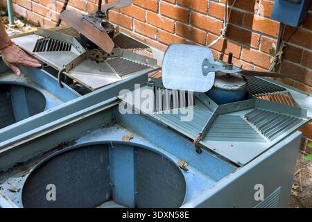 Il tecnico lavora per il fissaggio di due unità di climatizzazione situate all'esterno dell'edificio in mattoni in un quartiere residenziale. Foto Stock