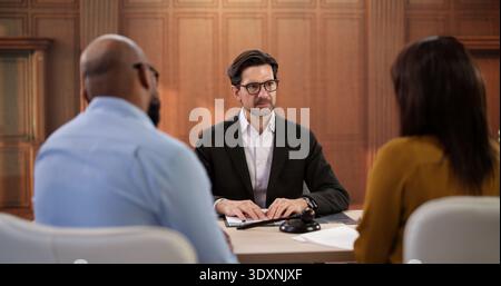 Una giovane coppia discute importanti questioni legali con Un consulente professionale. Un uomo africano Foto Stock