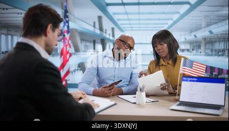 La giovane coppia incontra l'avvocato che prepara il visto intervista, discutendo i piani di viaggio. Donne e uomini esaminano i documenti su un notebook Foto Stock