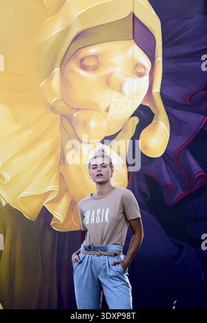 Ogni individuo si erge con sicurezza contro un grande murale colorato, vestito in modo informale in un'area urbana, donna elegante, alla moda, elegante, alla moda, in voga, Foto Stock
