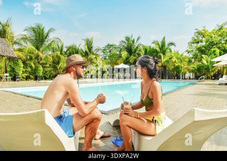 Giovane coppia adulta innamorata e divertendosi a bere caffè fresco freddo e ghiacciato chiacchierando durante le vacanze nel soleggiato sud-est asiatico tropicale. Coupl europea Foto Stock