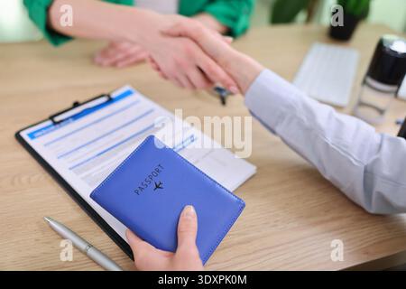 Stretta di mano tra due professionisti mentre i piani di viaggio prendono vita in un ambiente accogliente Foto Stock