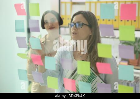 Sessione di brainstorming creativo con appunti adesivi in un ambiente d'ufficio vivace Foto Stock