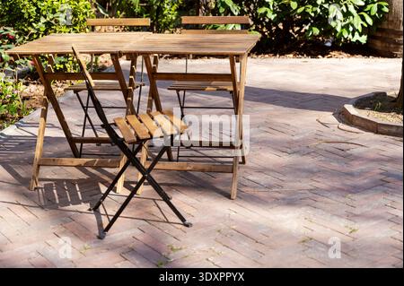 Tavoli e sedie pieghevoli vuoti in legno presso una terrazza esterna del ristorante Foto Stock